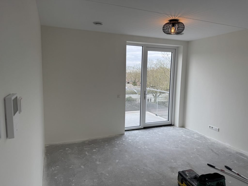Lege, lichte kamer met openslaande deuren naar een balkon, klaar om ingericht te worden